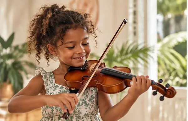 Une petite fille joue du violon en souriant